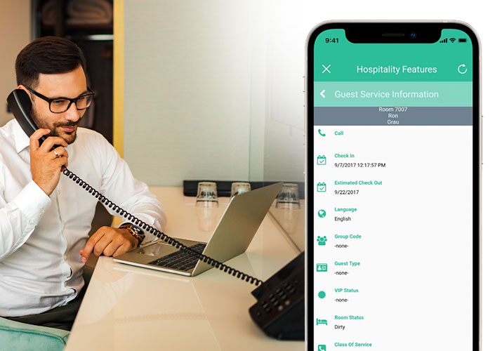 A young white male in a white button up shirt and glasses uses his hotel's new cloud-based phone system from SONIFI and Ooma